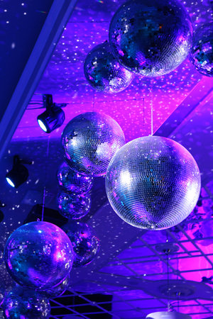 Disco ball with bright rays, night party with blue background. Party dance hall celebration at night club with lots of flashy colors. Rotating disco mirror ball.Vertical photo.の写真素材