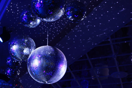 The concept of disco. Light and music disco ball on a blue background. A rotating disco ball in a nightclub with glittering effects. A spinning sparkling mirror disco ball spinning in the lights of a nightclub. The atmosphere of the party.の写真素材