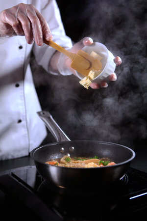 The process of making risotto. The chef prepares risotto with seafood. Unrecognizable vertical photo without a face.の写真素材