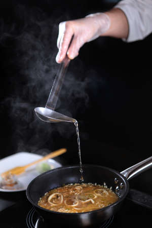 Fish broth is added to risotto. Cooking risotto with seafood. Vertical unrecognizable photo.Natural collagen.の写真素材