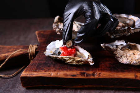Decoration of fresh oysters with a prepared sauce made from berries and olive oil. Unrecognizable photo. Close up.の写真素材