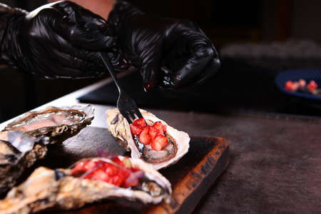 The sauce of berries and olive oil is spread on fresh oysters. Oyster season. .Unrecognizable photo. Close up.の写真素材