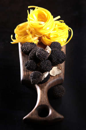 Cooking a dish of truffles and pasta. Delicious and expensive mushrooms.Black truffles and pasta in the form of nests on a wooden Board.Top viewの写真素材
