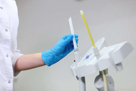 A dental assistant holds a dental instrument in his hand.Preparing the office for receiving patients. The concept of hygiene and sanitation. Unrecognizable person.Copy space.の写真素材