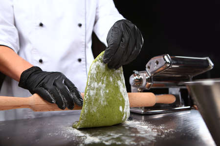The chef prepares pasta with spinach. Close up. Unrecognizable person.Machine for preparing pasta or...