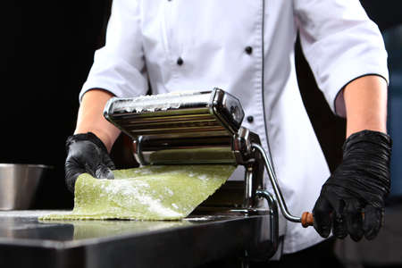 The chef prepares pasta with spinach. Close up. Unrecognizable person.Machine for preparing pasta or...
