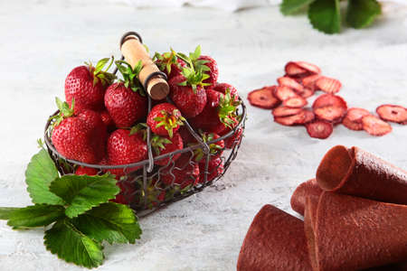 Strawberries in a wicker metal basket and strawberry marshmallows on a poor background. View from above. Copy space. Healthy food concept. Dried berry slices.の写真素材