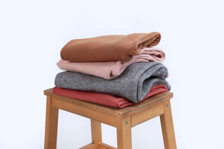 Knitted woolen clothes lie on a wooden chair. Clothes made of natural wool for the cold season....