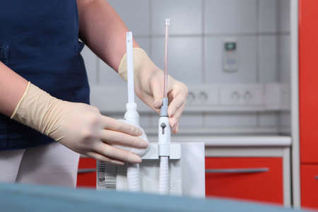 An employee of the dental clinic wipes the equipment in the surgical room. Disinfection of...