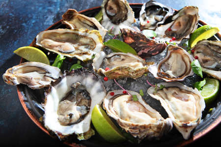 Fresh oysters with lime on a round plate. Oyster season. Macro-seafood dish. Oyster on the half...