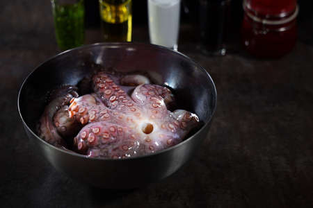 A whole octopus in a metal bowl.Close-up. Cooking octopus. Photos without people. Dark background. Seafood dishes. Protein food.Free space.の写真素材