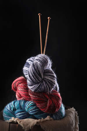 Colorful wool yarn with knitting needles on a black background. Yarn for hand knitting. The concept of a hobby.Free space. Vertical photo.の写真素材
