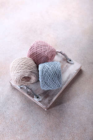 Three skeins of delicate yarn on a wooden tray. Natural wool yarn.Hobby concept.Handmade work. Free...