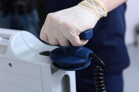 Resuscitator doctor holds an electrode in his hand. Preparing for defibrillation. Equipping a modern...