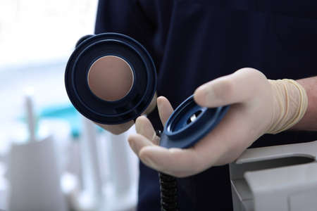 Applying special composition to teeth for subsequent enamel whitening. Teeth whitening in dental clinic with cold light lamp. Dental procedure. Unrecognizable faces. Top view.の写真素材