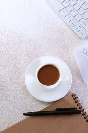 A cup of coffee on the desktop.Computer and notepad for writing on a light background. Keyboard for...