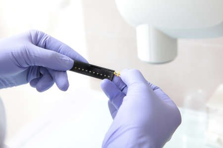 Drill for penetration into the dental canals. The doctor measures the length of the drill. Close-up....