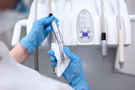 Disinfection of dental equipment. Doctor's assistant wipes equipment in dental clinic. Dental movable console. Health care concept. Beyond recognition. Top view.の写真素材