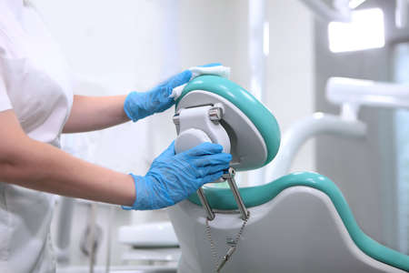 Dental assistant wipes the dental chair. Disinfection of dental equipment. Health care concept.Unrecognizable person.の写真素材
