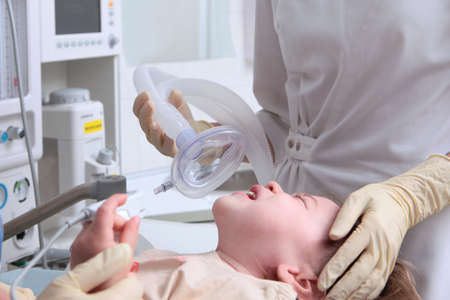 The childs exit from anesthesia. The baby is crying. Anesthesia for a child. The work of a physician reaoimatologist and anesthesiologist. Life saving.Oxygen mask.の写真素材