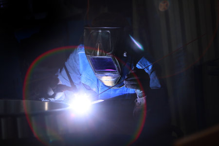 Working profession is a welder. Bearing parts in production. Worker in a welder's helmet. The...