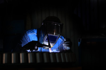 Work of a welder in production. Profession with risk to life. Worker in a helmet of a welder....