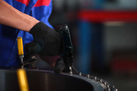 Worker assembles the bearing by hand. Large diameter bearing is assembled at the factory. Bearing production. Heavy industry. Unrecognizable person. Only hands.の写真素材