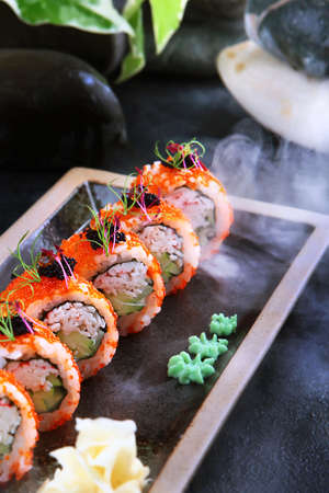Rolls California with crab.Traditional Japanese cuisine. Rolls with shrimps, tobiko caviar and cucumber. Healthy food. Vertical photo.Out of focus. Photo on black background with smoke.の写真素材