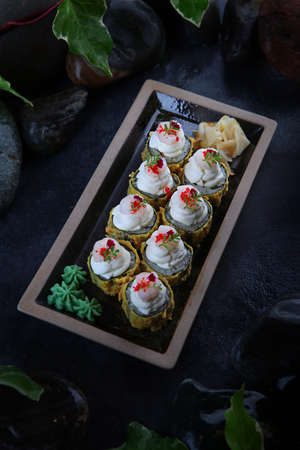 Rolls in tempura with mussels. Traditional Japanese cuisine. Raspberry tobik caviar. Ebi tempura. White ginger. Cocktail shrimp. Vertical photo on black background.Top view.の写真素材