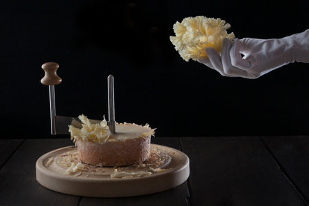 Cheese tete de moine. Special girolle knife. A hand in a white glove holds tete de moine cheese cut into thin shavings. Photo on black background.の写真素材