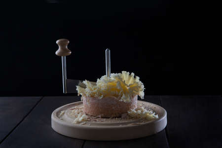 Tete de moine cheese. Special girolle knife. The tete de moine cheese is cut into thin shavings. Photo on a black background. Photo on black background. With copy space.の写真素材