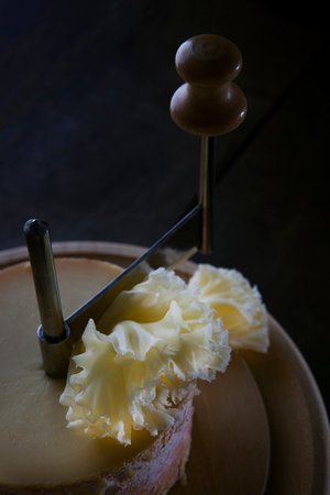 The tete de moine cheese is cut into thin shavings. Special girolle knife. Close-up. Photo on a black background.の写真素材