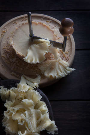 The tete de moine cheese is cut into thin shavings. Special girolle knife. Photo on a black background. Top view.の写真素材