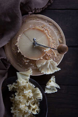 The tete de moine cheese is cut into thin shavings. Special girolle knife. Photo on a black background. Brown cotton napkin. View from above.の写真素材