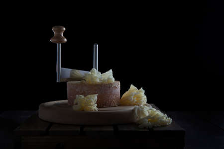 Elite Swiss cheese tete de moine is cut into thin shavings using a special girolle knife. Black background. With copy space. Wooden stand.の写真素材
