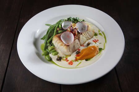 Pike perch with white sauce and beans. A white plate. Menu for the restaurant. Healthy and low-calorie food. A dish of fish with beans.Close-up.の写真素材