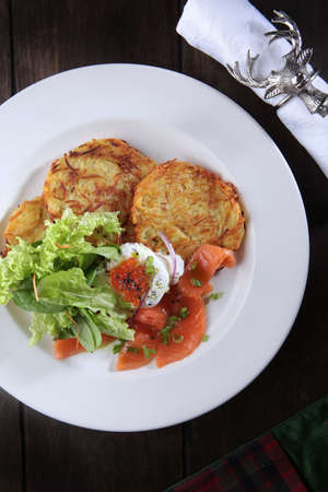 Potato pancakes with red salmon fish. Caviar and poached egg on potato pancakes. The concept of the restaurant menu. Festive serving with a glass of mulled wineの写真素材