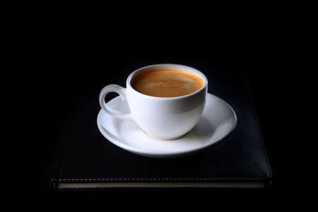 A cup of coffee is on a notepad for notes.Top view.Business breakfast.Food and drinks.Coffee break....
