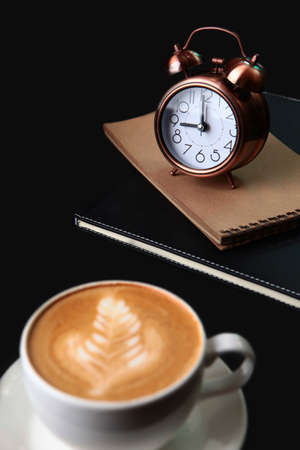 Alarm clock and notepad for notes.The coffee cup is out of focus.Food and drinks.Coffee break. Space...
