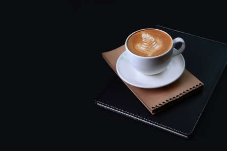 Cup of coffee on black background. Notepad for writing on a black background . The concept of a business breakfast or coffee break. Spiral notebook for notes.Vertical photo.Copy space.の写真素材