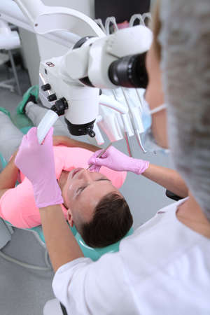 Dentist appointment.A female dentist treats a patient under a microscope.Modern dentistry. A man at a dentists appointment. Dental examination. Prevention of dental diseases.の写真素材