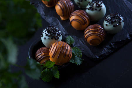 Handmade round shaped candies. A tin vase with a lid. Belgian chocolate of the highest quality. Dessert for the holiday. Black background.の写真素材