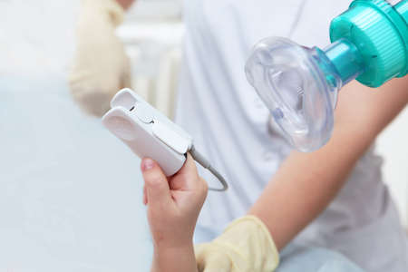 Child's hand with a device for measuring the level of oxygen in the blood in close-up.Device for measuring oxygen concentration. general anesthesia. Preparing the child for surgery.Copy space.の写真素材