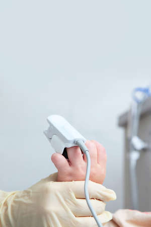 Child's hand with a device for measuring the level of oxygen in the blood in close-up.Device for measuring oxygen concentration. general anesthesia. Preparing the child for surgery.Copy space.の写真素材