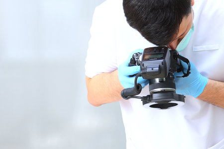 The dentist takes pictures. The camera is in the doctors hands. Photo protocol. An unrecognizable person. Photo in the clinic. Concept of prevention and treatment of diseases. Copy space.の写真素材