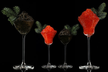 Caviar is black and red in tall glasses. The wine glasses are decorated with fir branches. A festive snack.Salmon caviar. Delicacies.Space for text. Black background. New Year or Christmas.の写真素材