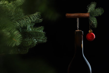 A bottle of wine with a wooden corkscrew. Spruce branches. Christmas tree toy in the shape of a...