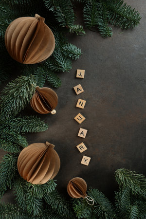 Christmas toys made of handmade paper. Handmade work. Craft paper. Wooden letters with the word January on a dark background. Fir branches. Flat view.Space for text. Vertical photo.の写真素材