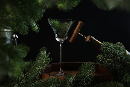A bottle of wine with a wooden corkscrew on a black background. New Years concept. Fir branches in a wine glass. New Year or Christmas. Winter season.の写真素材