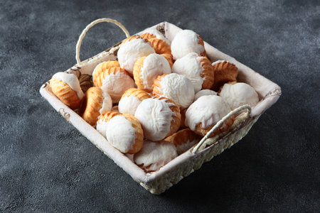 A basket with cupcakes on a gray background. Cupcakes in large quantities are in basket. White icing on cupcakes. Baking for the Easter holiday.の写真素材